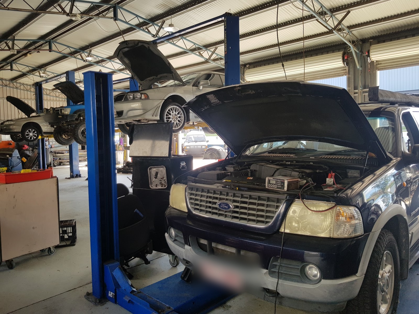 Inside the workshop: four two-post hoists with vehicles up for service